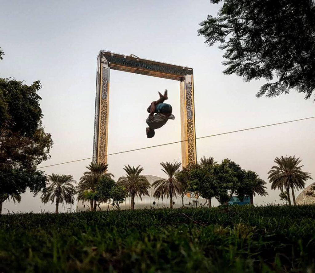 Slackline backflip through Dubai Frame at sunset