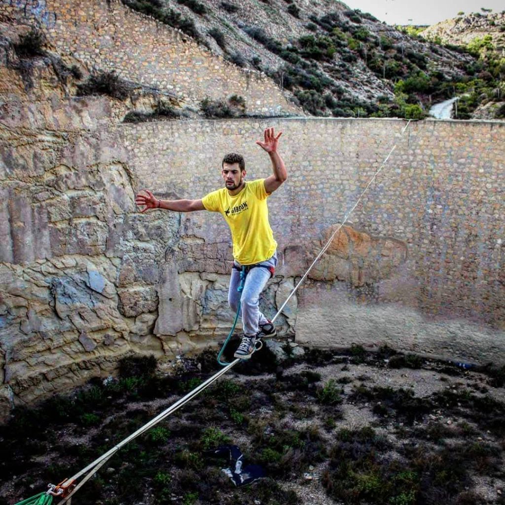 Carlos Merayo slacklining in outdoor rocky terrain